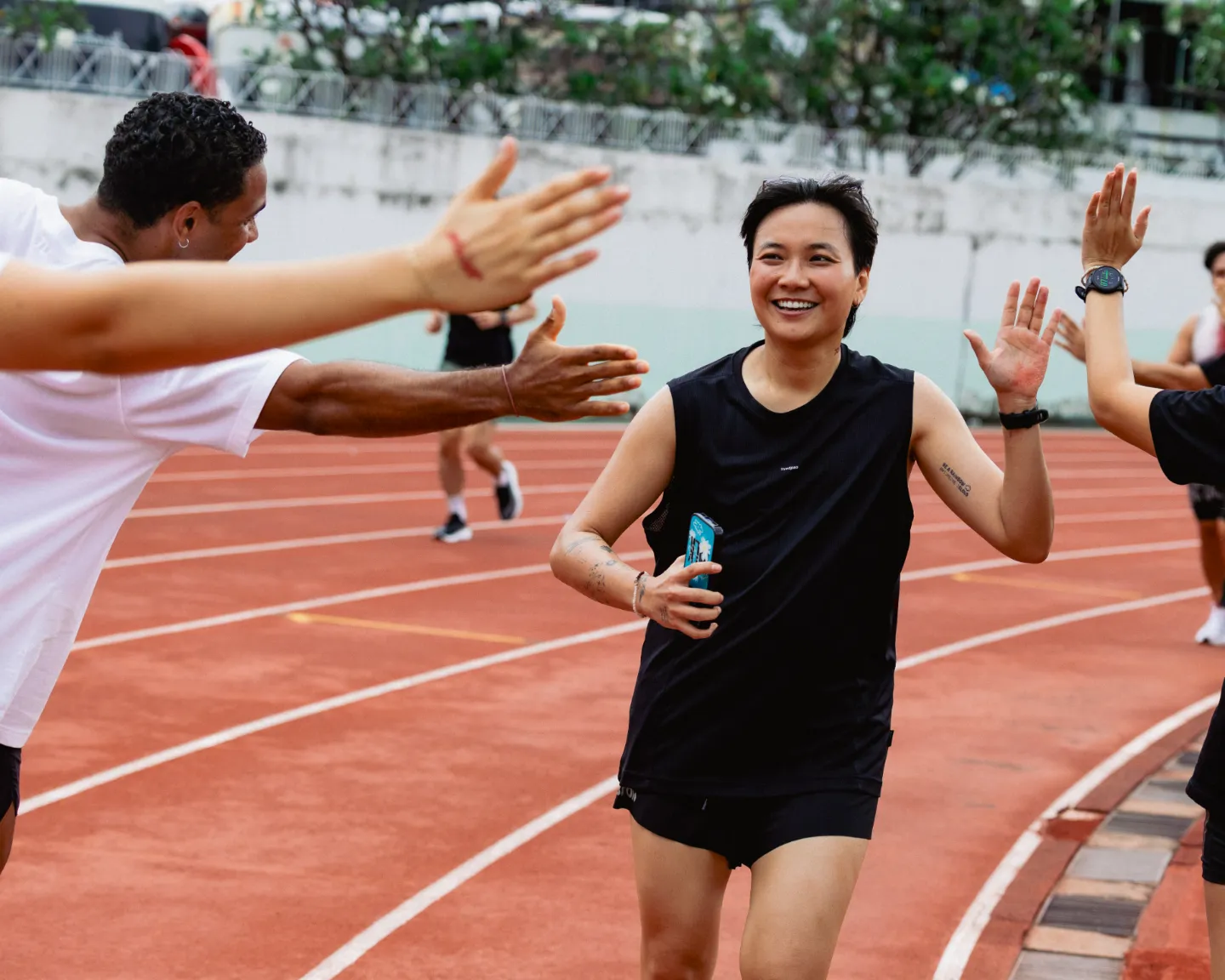 Runner smiling as teammates high-five her on the track